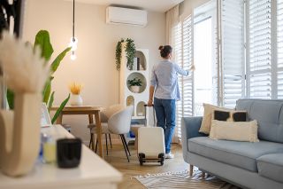 Foto: Frau öffnet Fenster in Wohnung